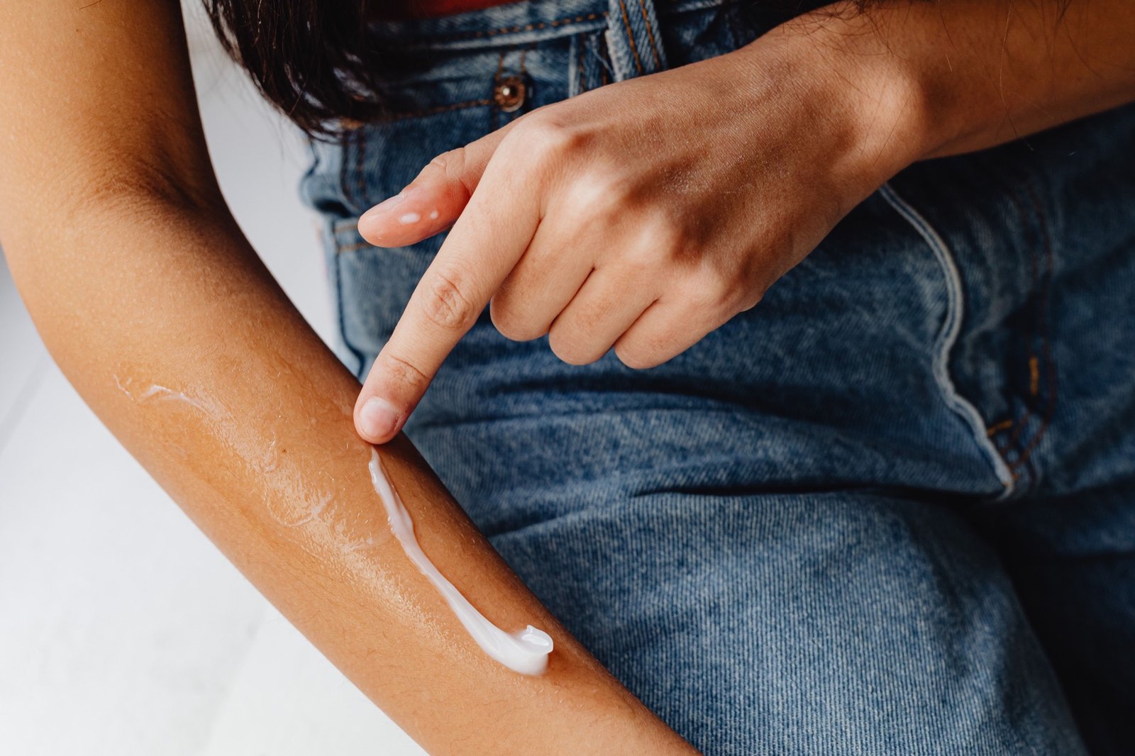 Applying moisturizing cream to the arm for eczema-prone skin