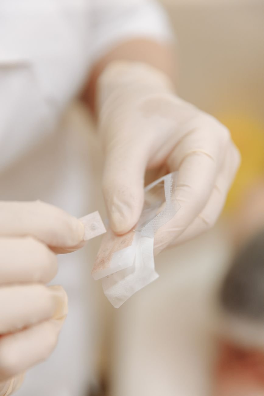 Gloved hands applying a sterile bandage during wound care