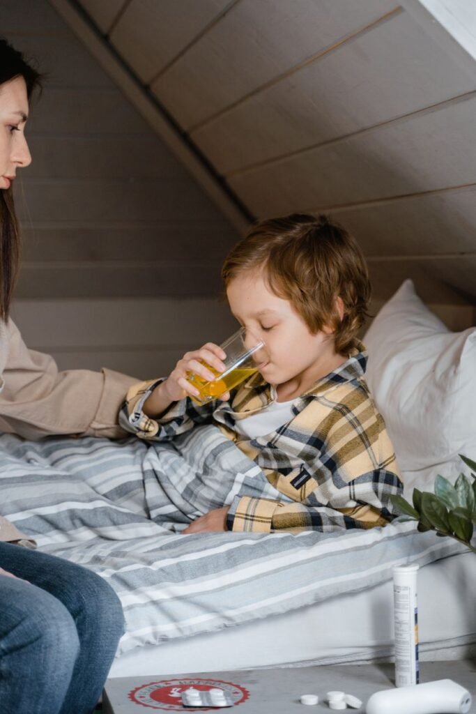 Young boy drinking a beverage while comforted by his mother