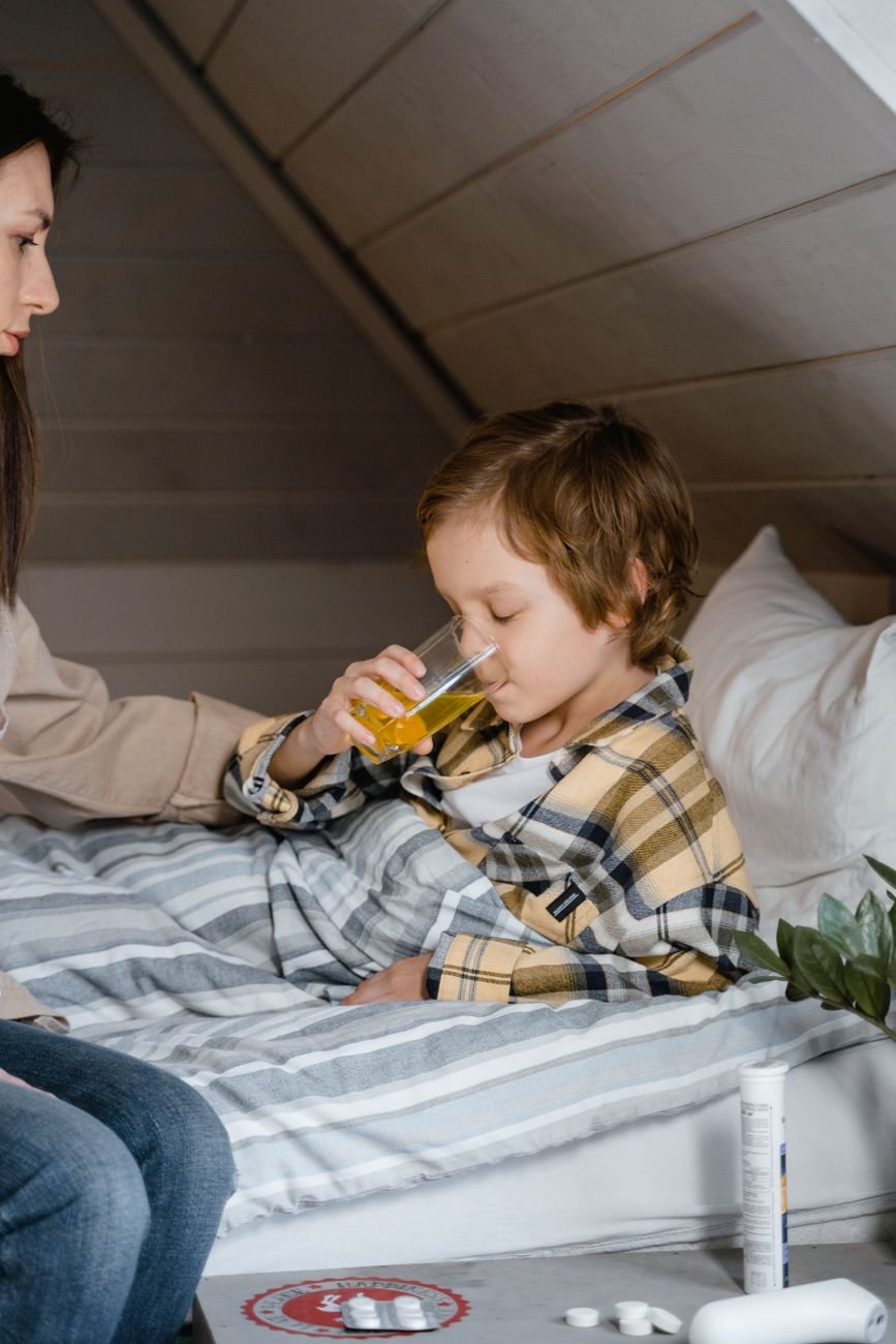 Young boy drinking a beverage while comforted by his mother
