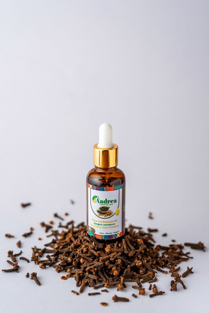 Bottle of clove oil surrounded by whole clove buds