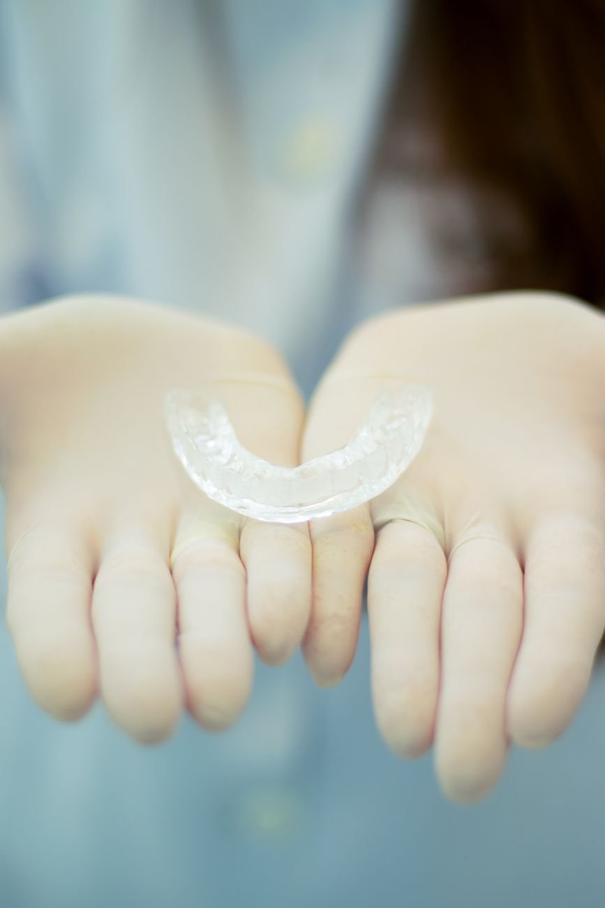 Gloved hands holding a clear dental mouthguard device
