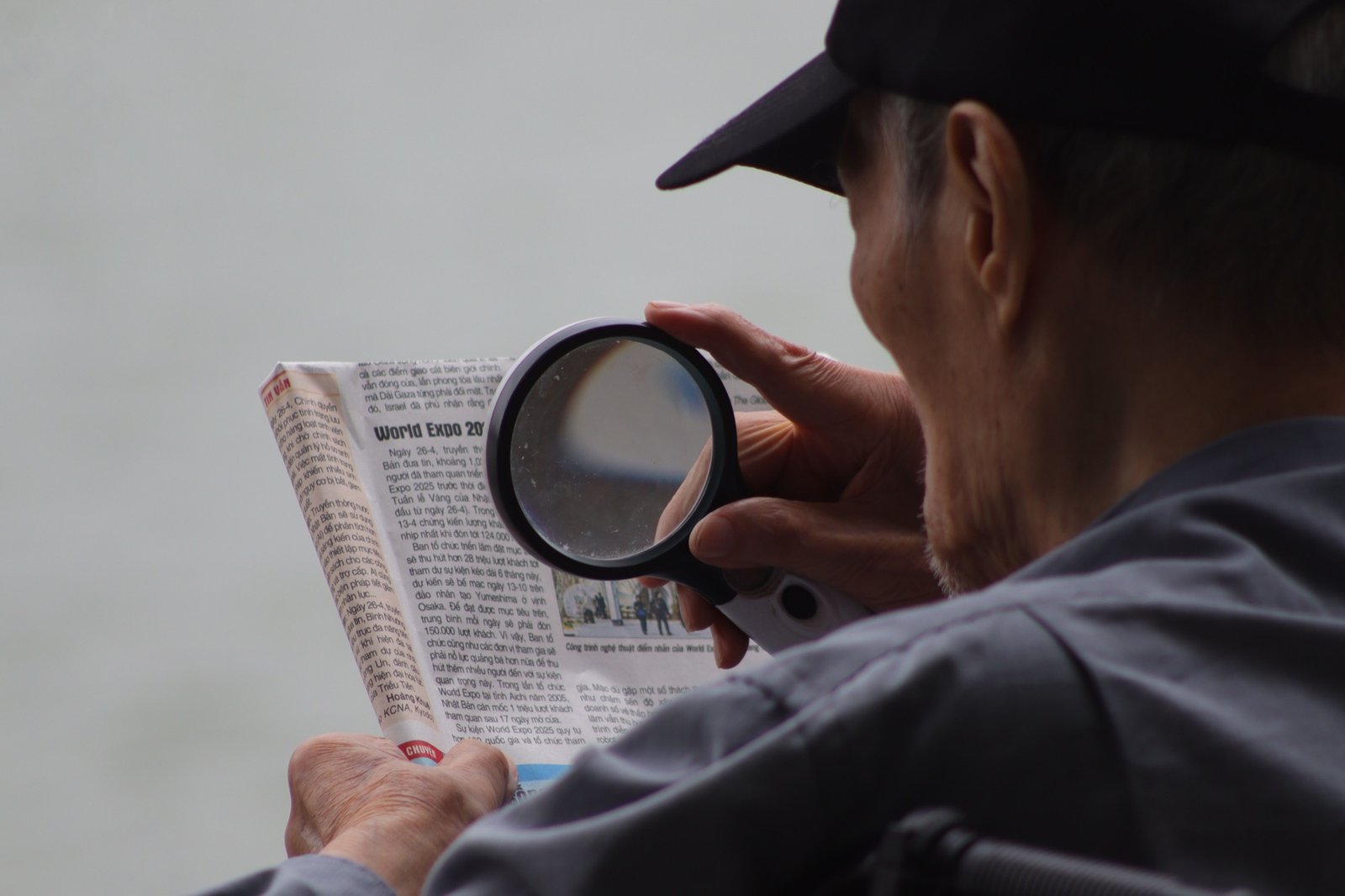 Elderly man using a magnifying glass to read due to clouded vision