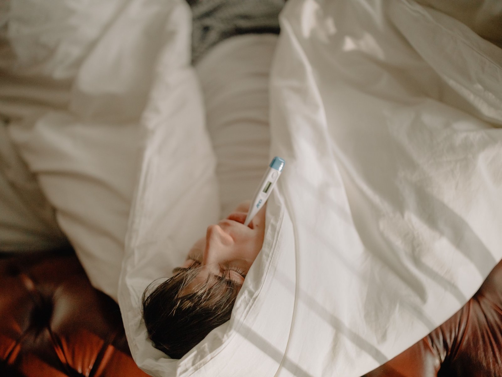 Man with a fever checking his temperature while sick with the flu