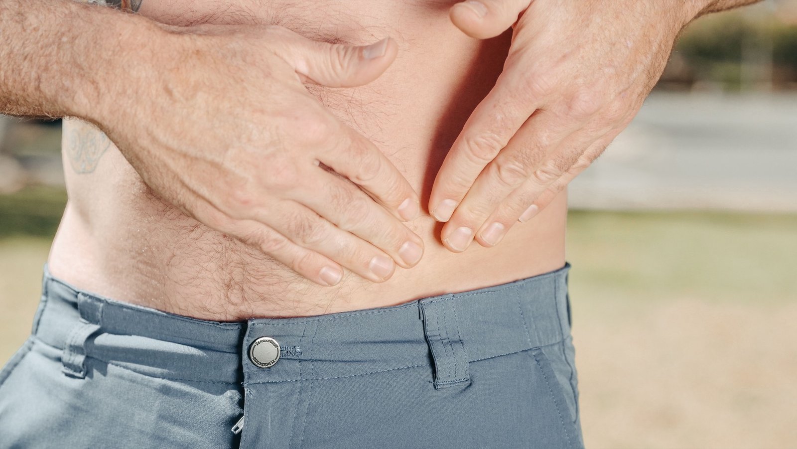 Person holding their lower abdomen due to hemorrhoid discomfort