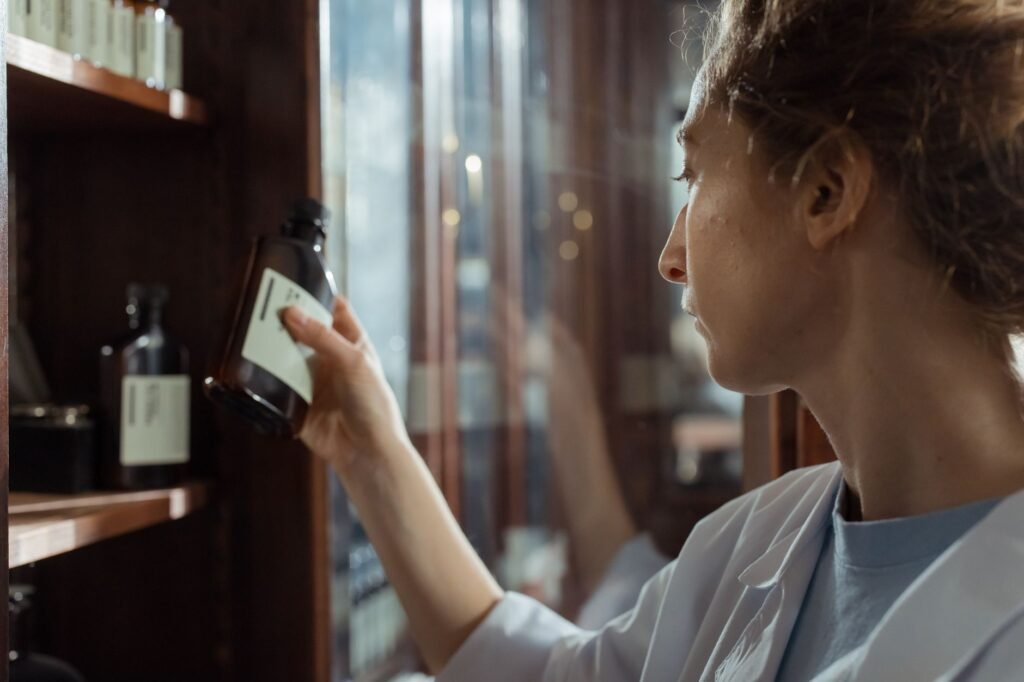 Pharmacist selecting a medication bottle from a pharmacy shelf