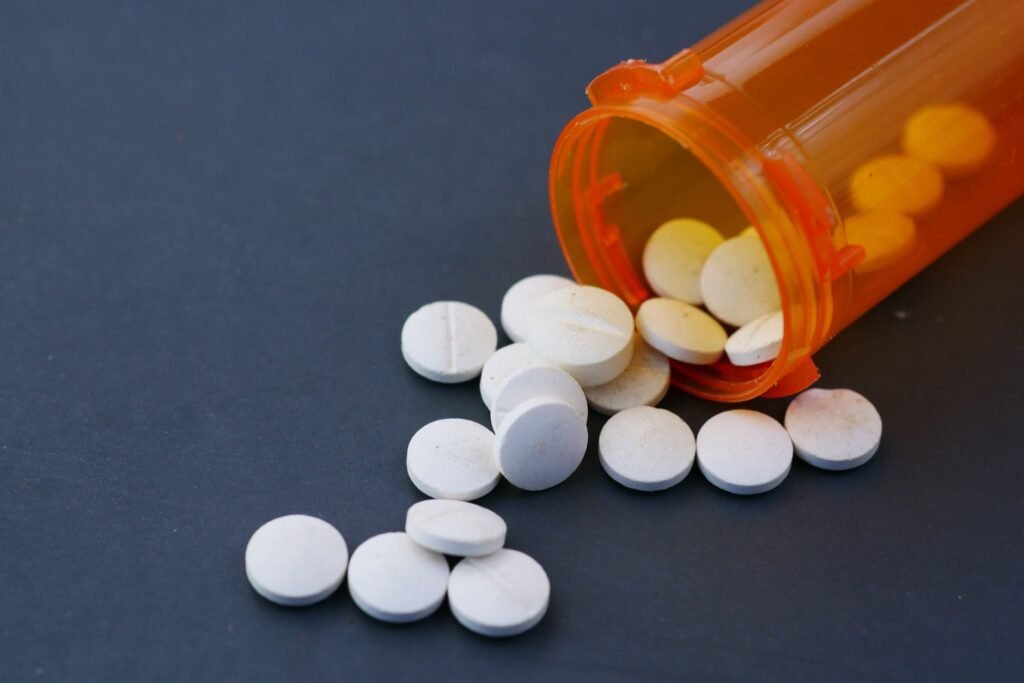 Prescription pills scattered from an orange pill bottle