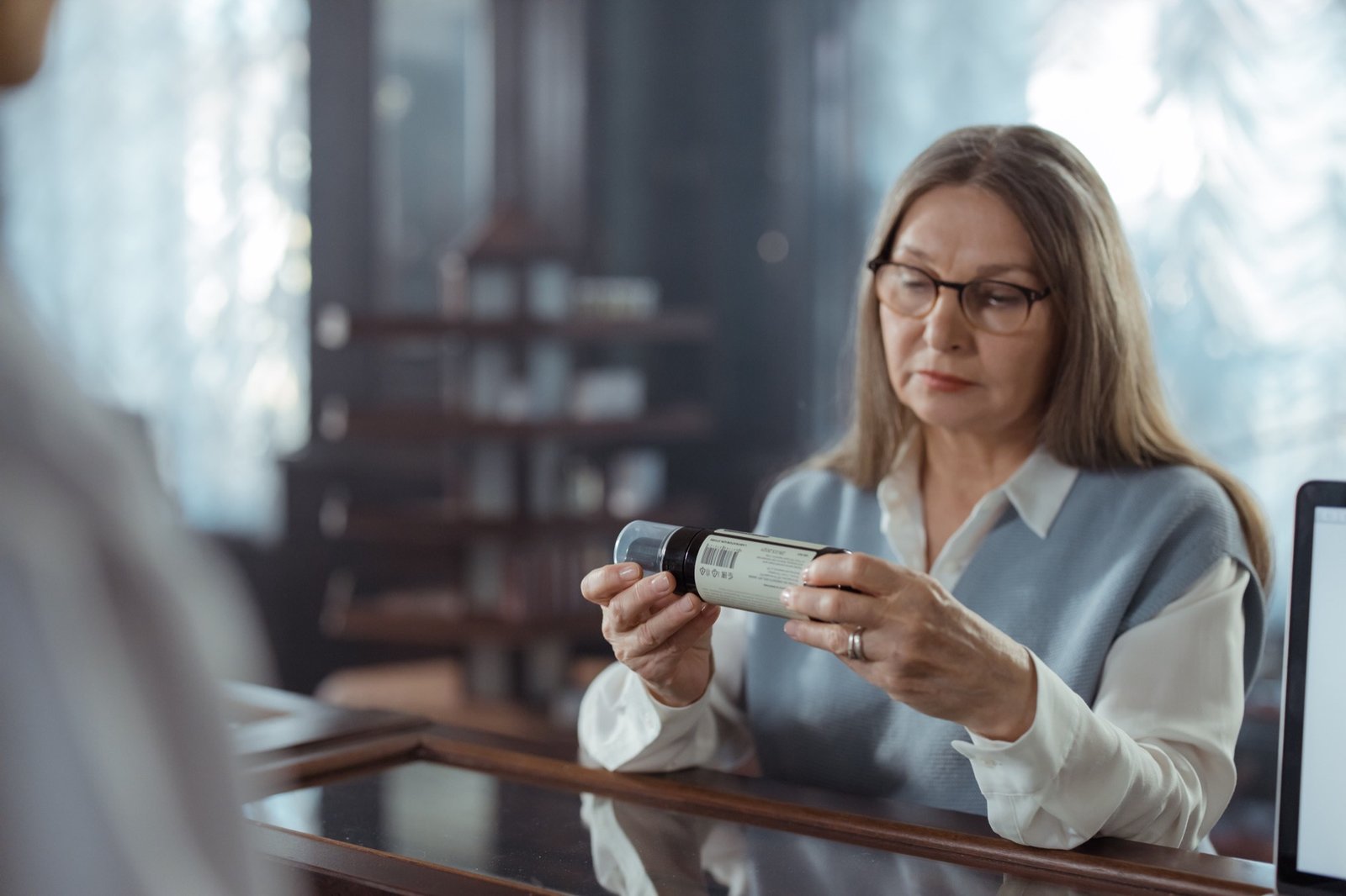 Senior woman reading a medicine label at the pharmacy counter