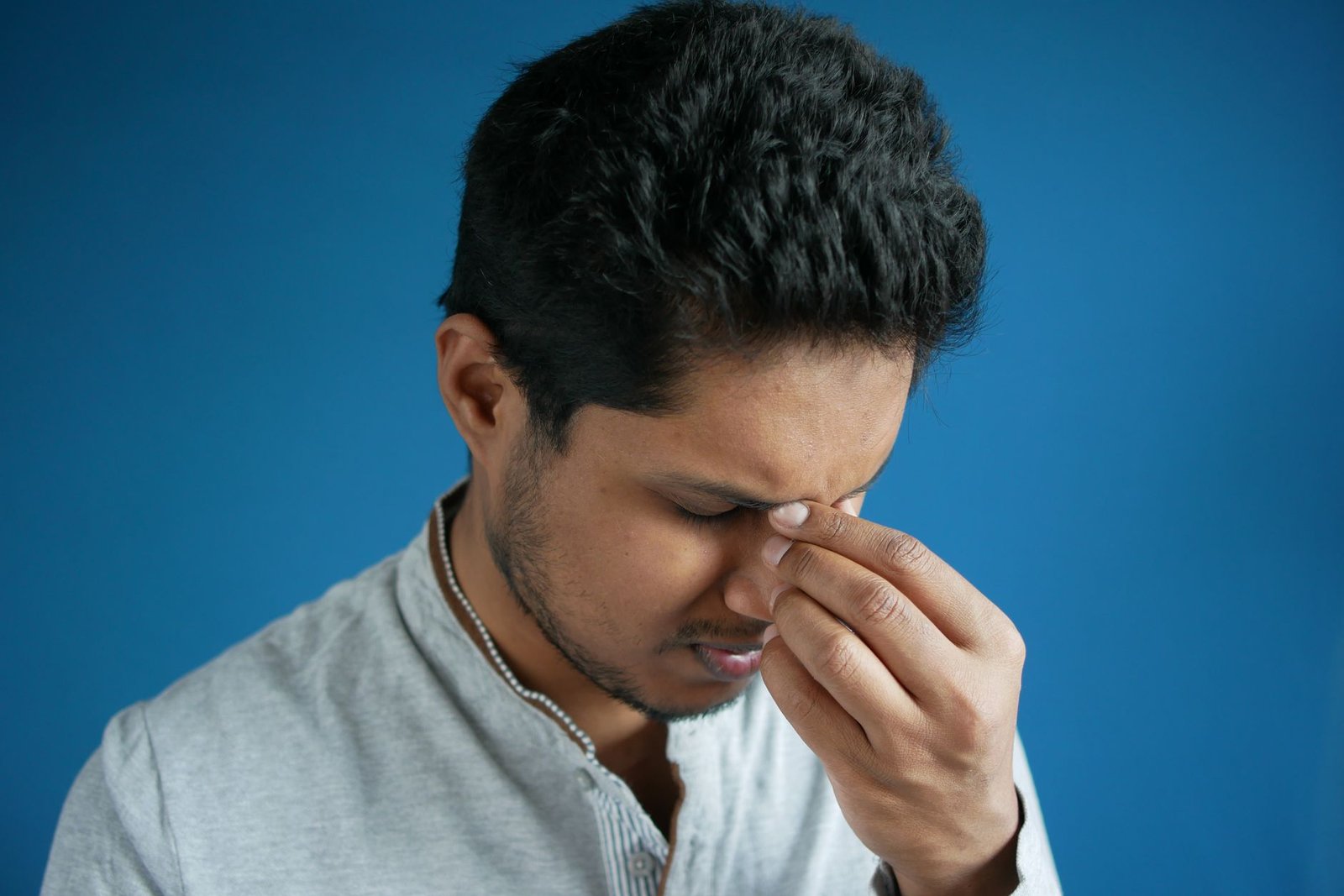 Man pinching the bridge of his nose from sinus pressure and headache