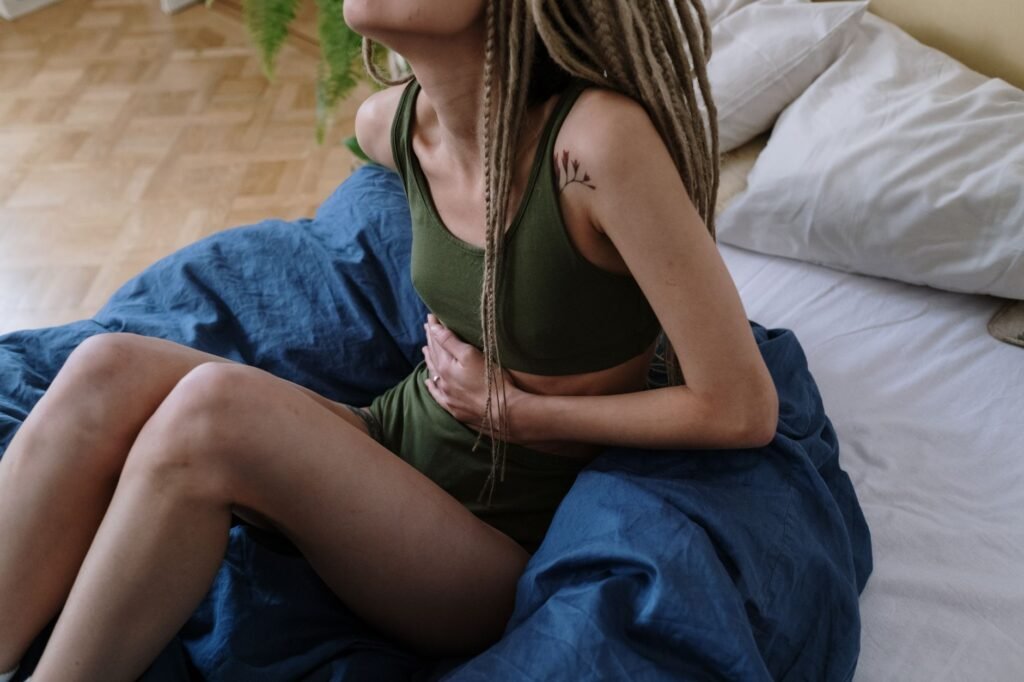 Woman in bed holding her stomach in discomfort from cramping