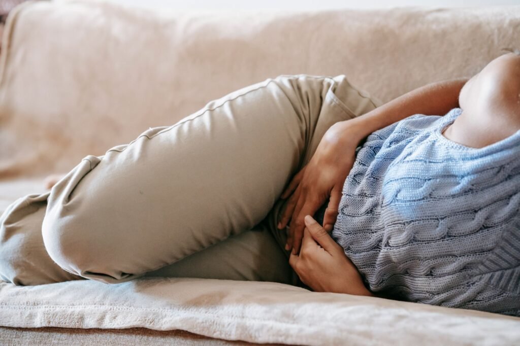 Woman lying on a sofa holding her stomach in discomfort