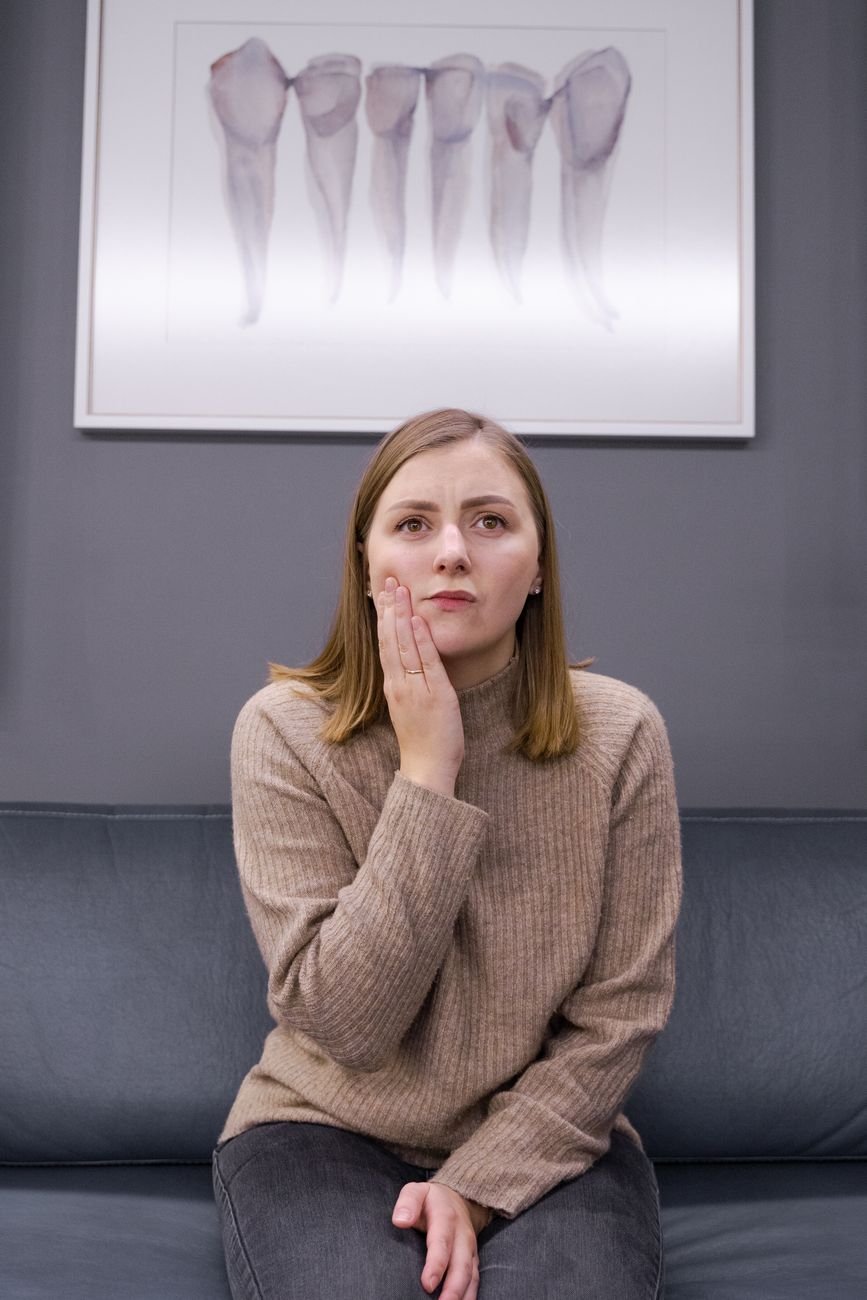 Woman holding her cheek in discomfort from tooth pain