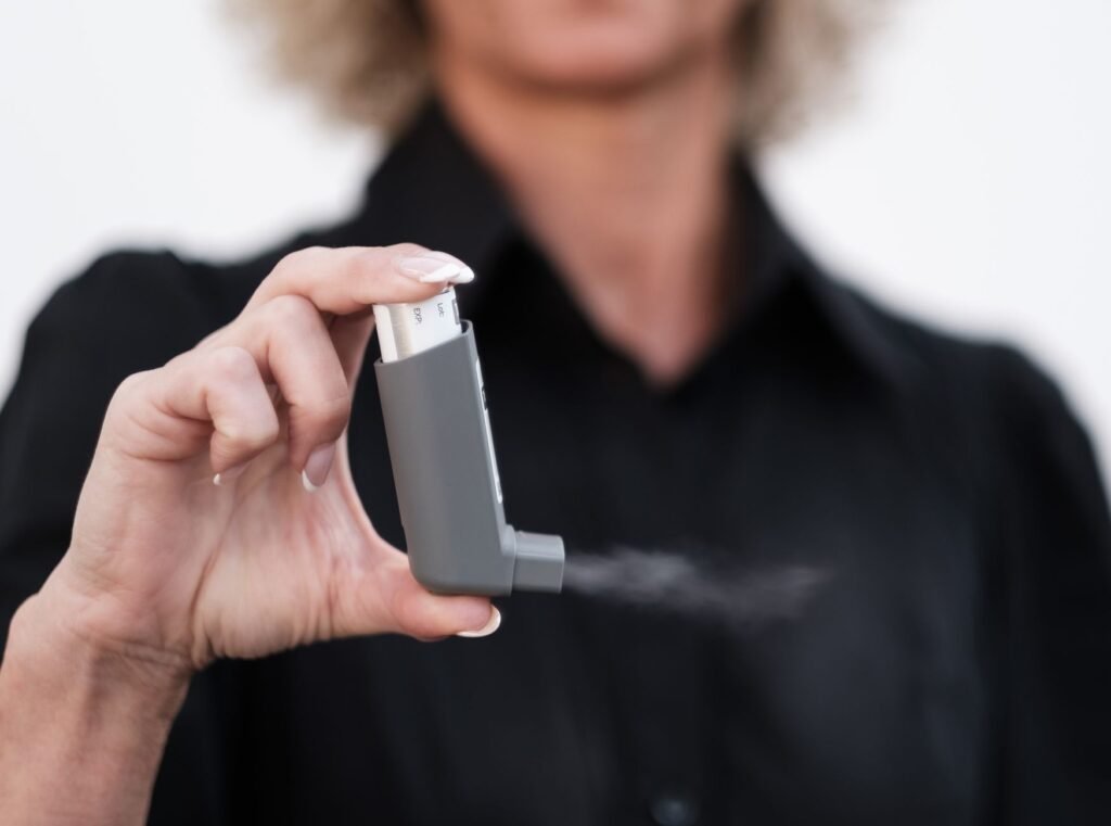 Person using a handheld inhaler for asthma symptoms