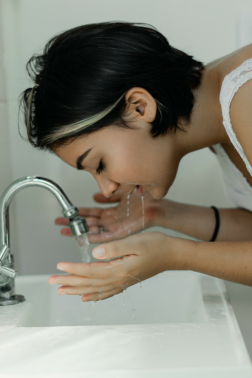 Woman washing her face at a bathroom sink