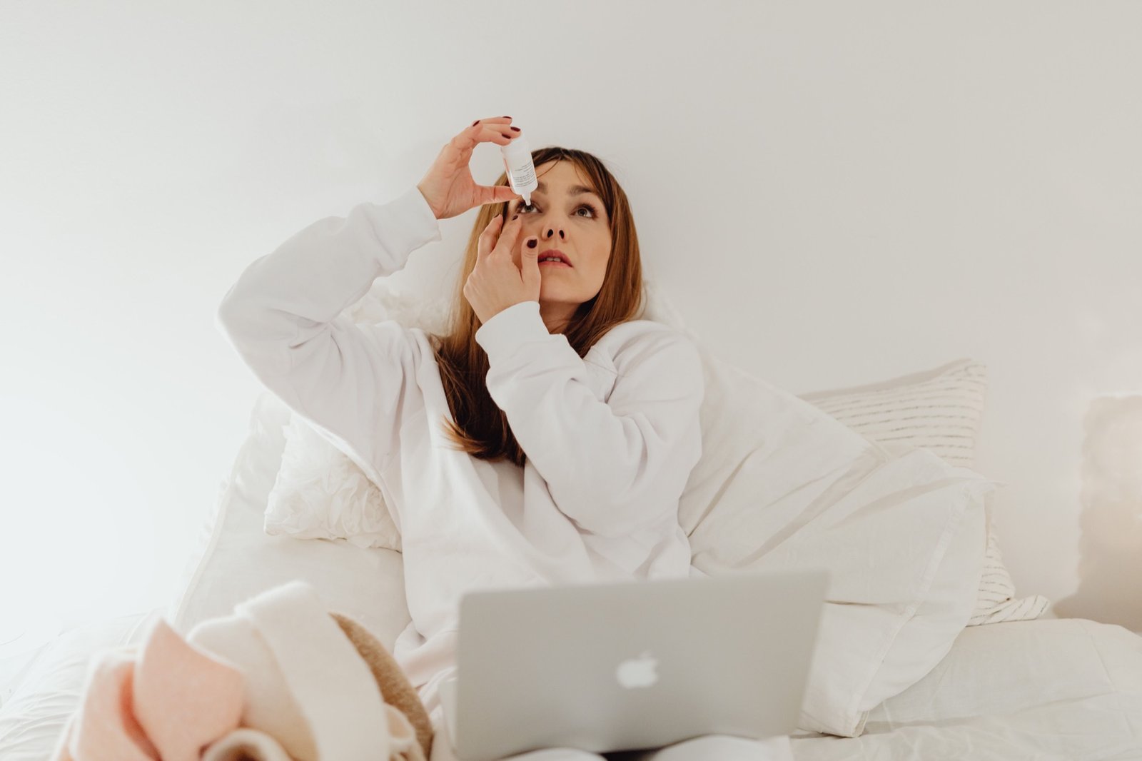 Woman applying antihistamine eye drops at home for allergy relief