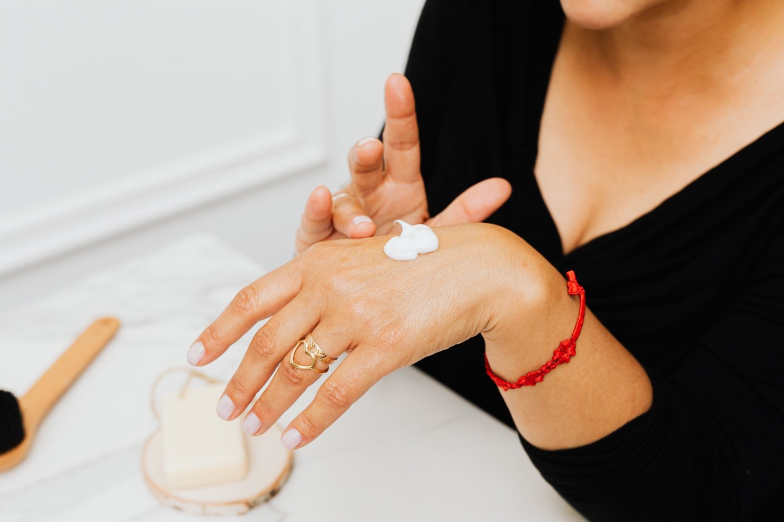 Woman applying moisturizing cream to her hands as part of a skincare routine