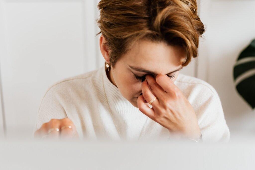 Woman rubbing her tired, dry eyes after prolonged screen use