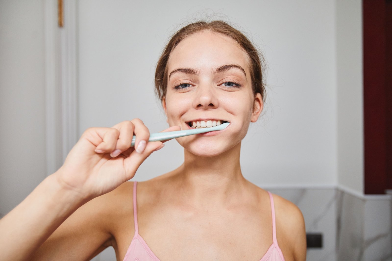Woman smiling while practicing daily oral hygiene