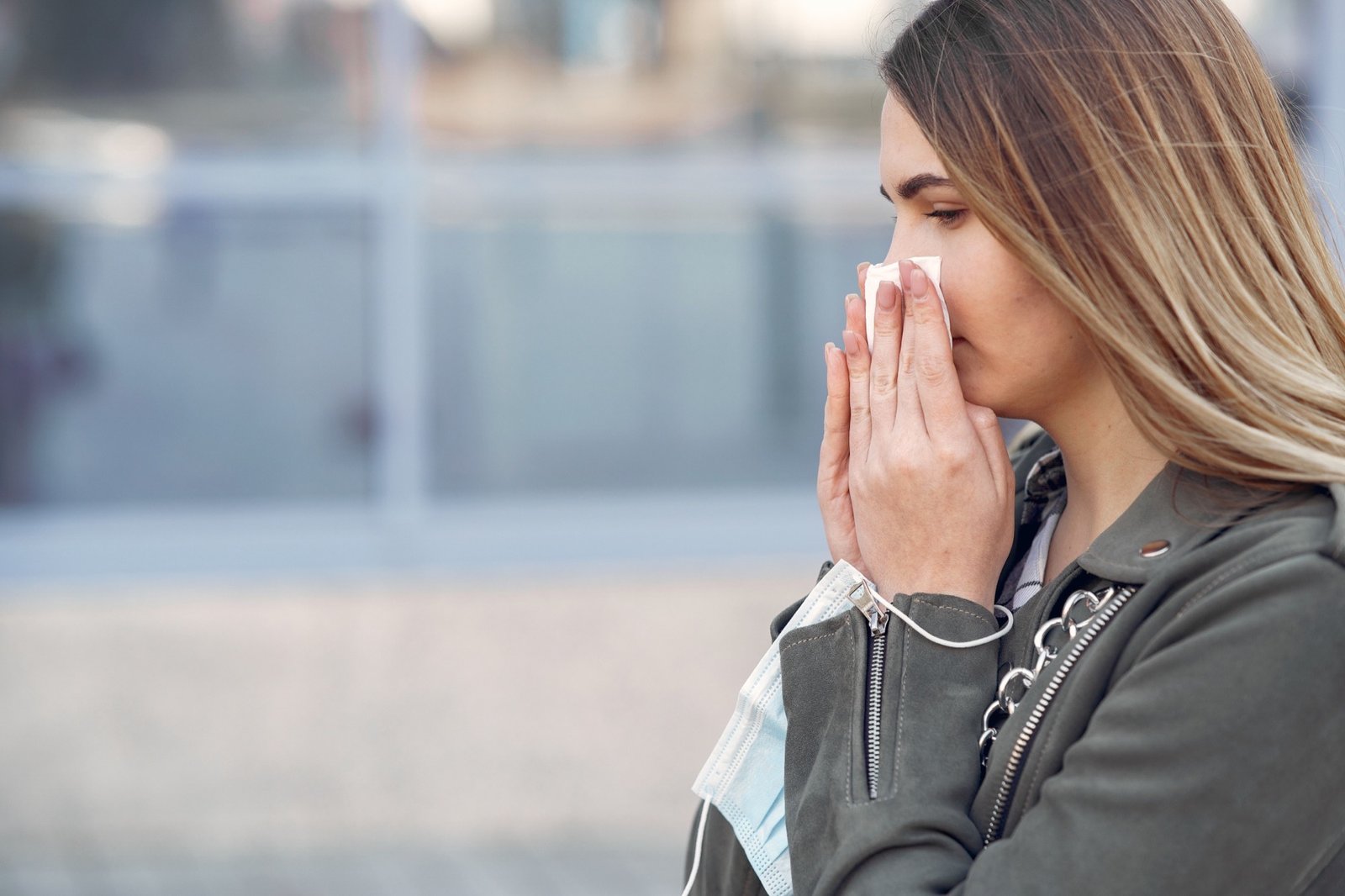 Woman sneezing outdoors during pollen season, a common trigger for seasonal allergic rhinitis