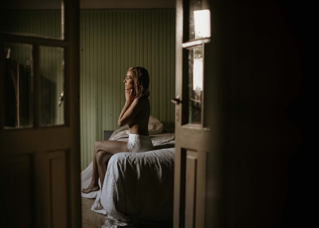 Woman sitting thoughtfully in a softly lit bedroom