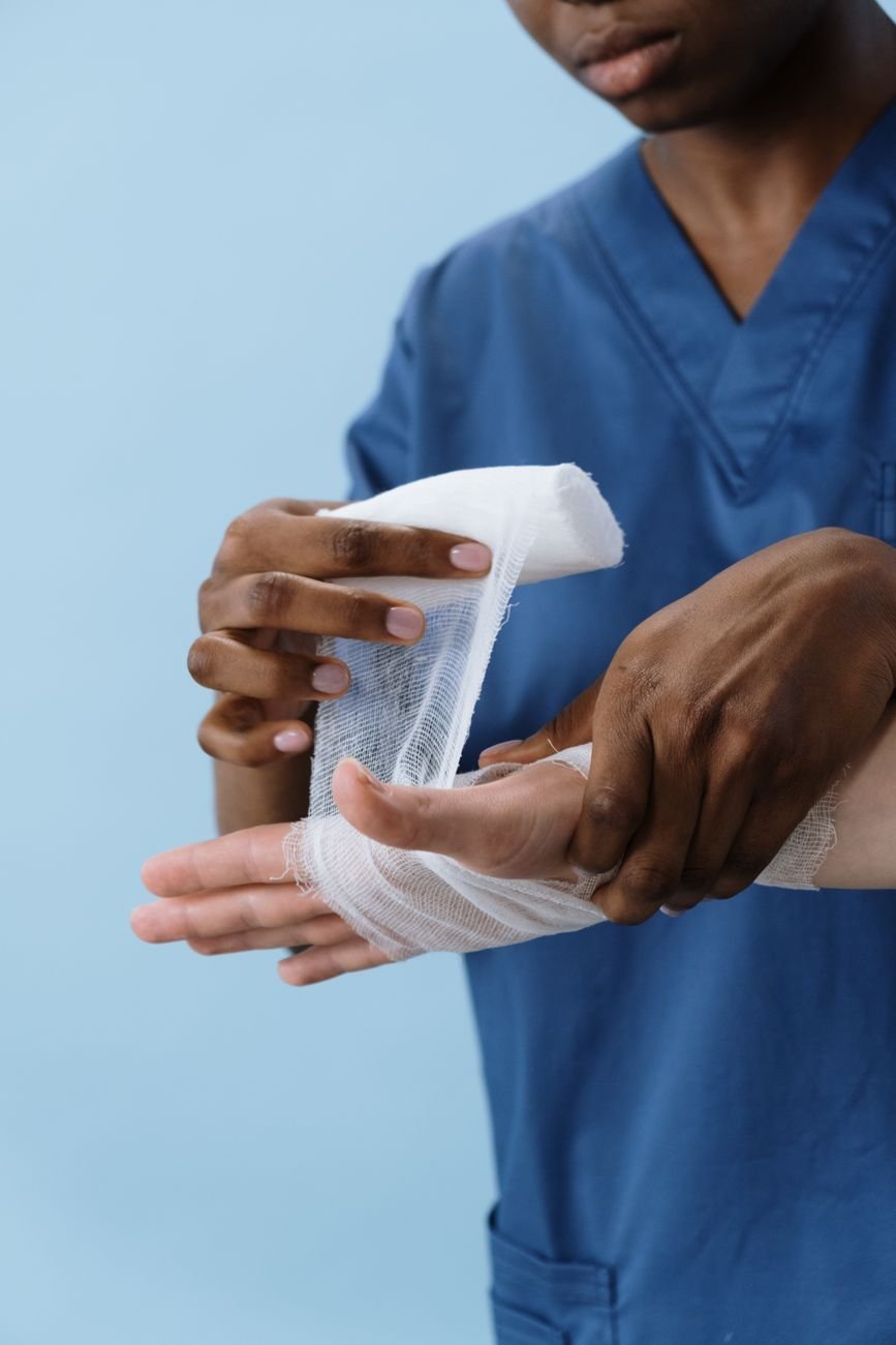 Healthcare professional wrapping gauze around a patient hand for wound care