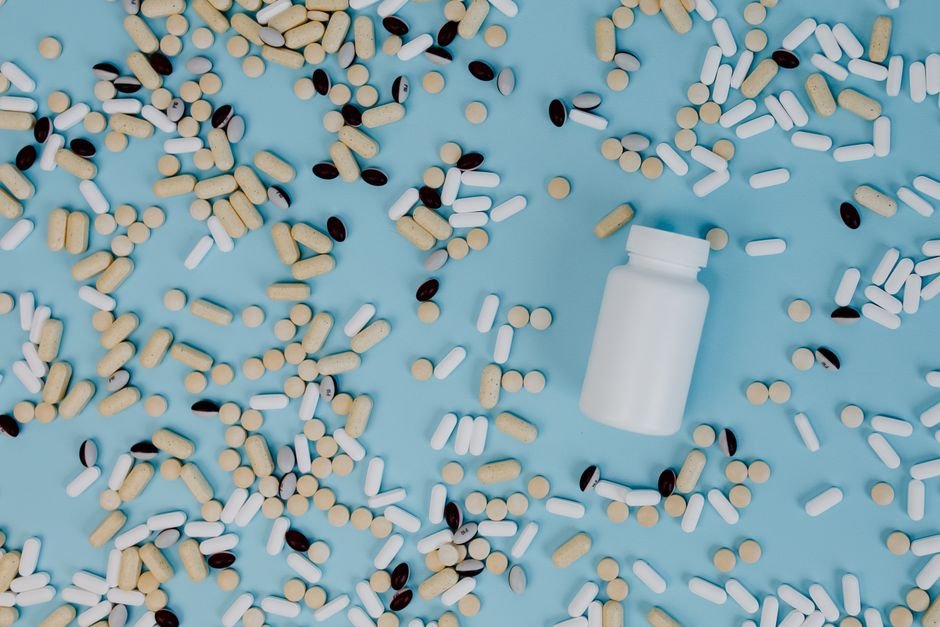 White capsule pills scattered on blue background