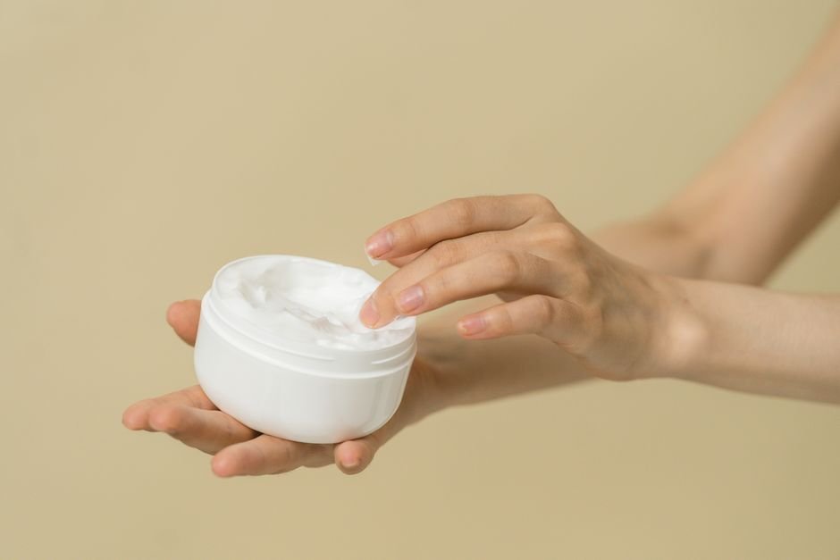 Hand applying cream from a jar