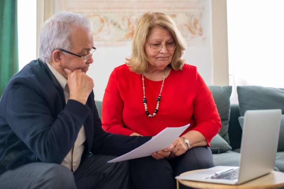 Older adult reviewing Medicare Part D insurance paperwork and medication costs at home