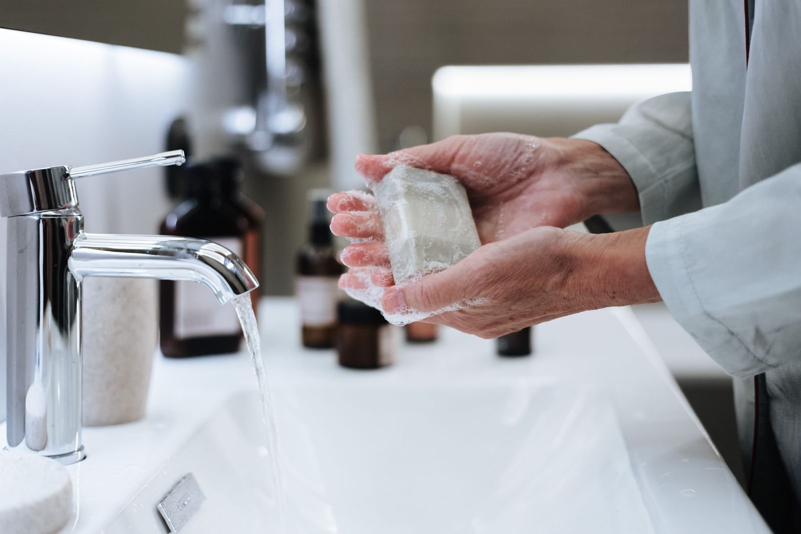 Hands washing with a bar of soap under running water before applying piles cream