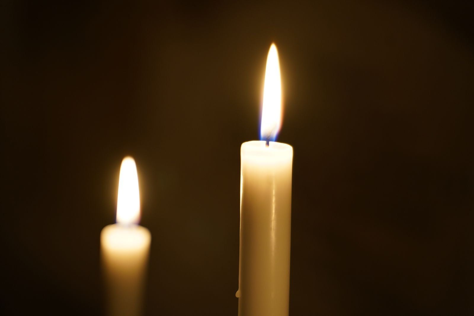 Two lit candles against a dark background, a reminder to keep Preparation H spray away from open flame