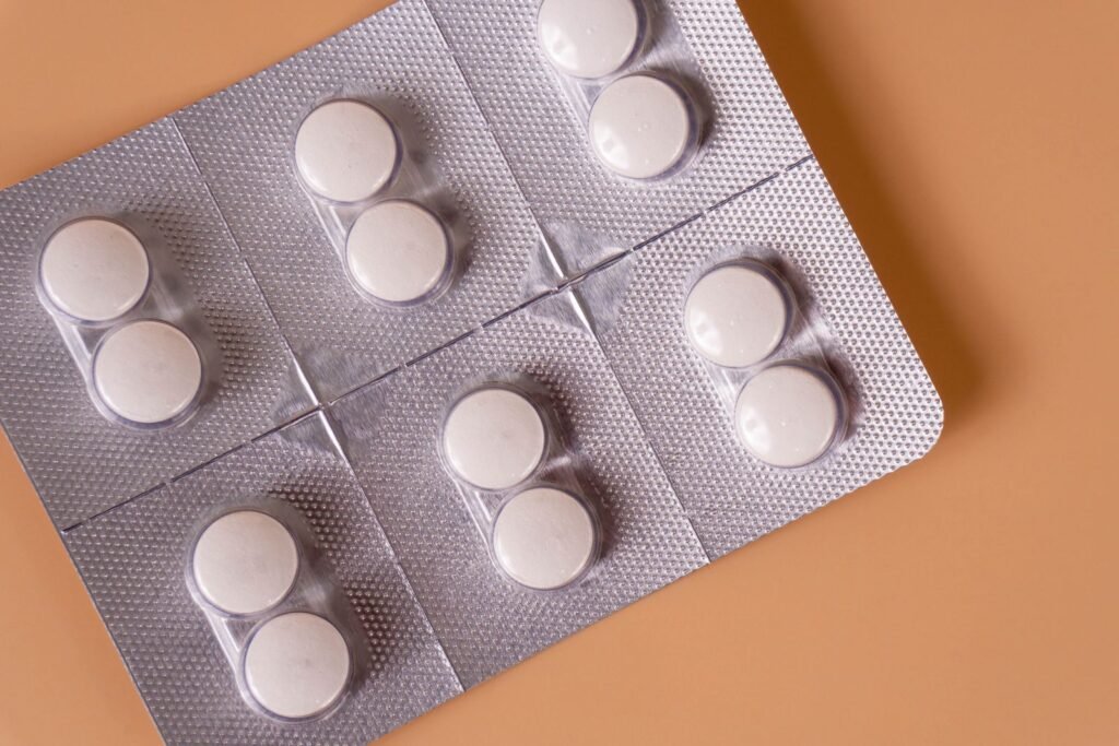 White medicine in a foil blister pack on an orange background, representing prescription hydrocortisone acetate suppositories