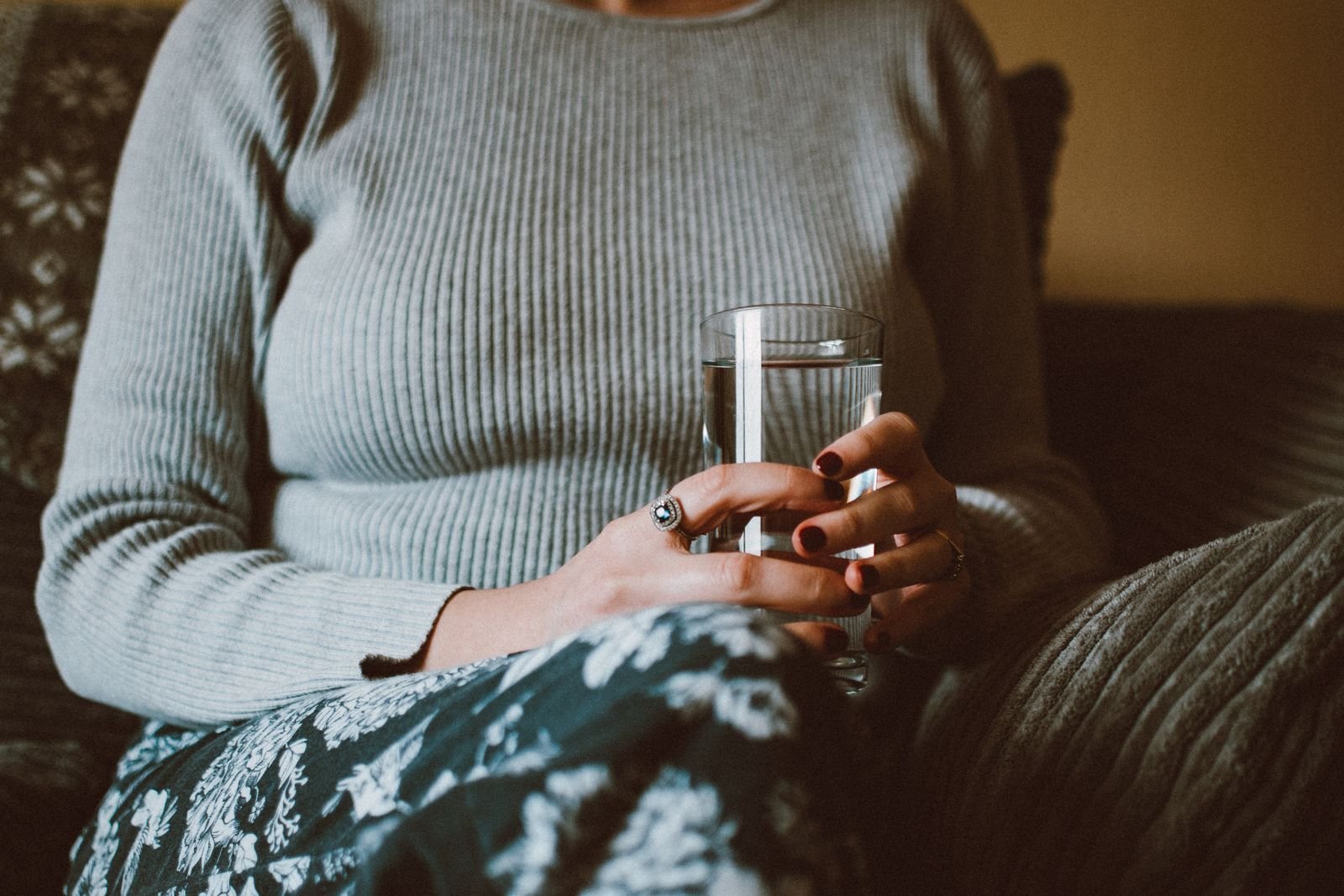 Woman holding a glass of water, illustrating that hemorrhoid suppositories do not make you poop like a laxative would