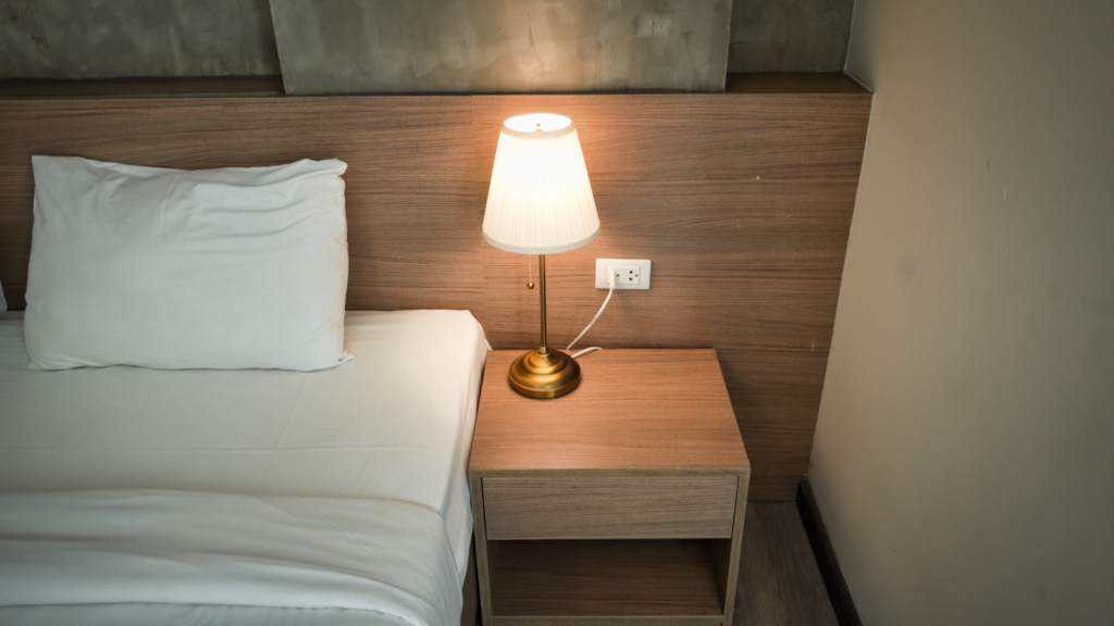 Bedside table with a lamp glowing beside a made bed, the nightly routine behind why take Colace at night