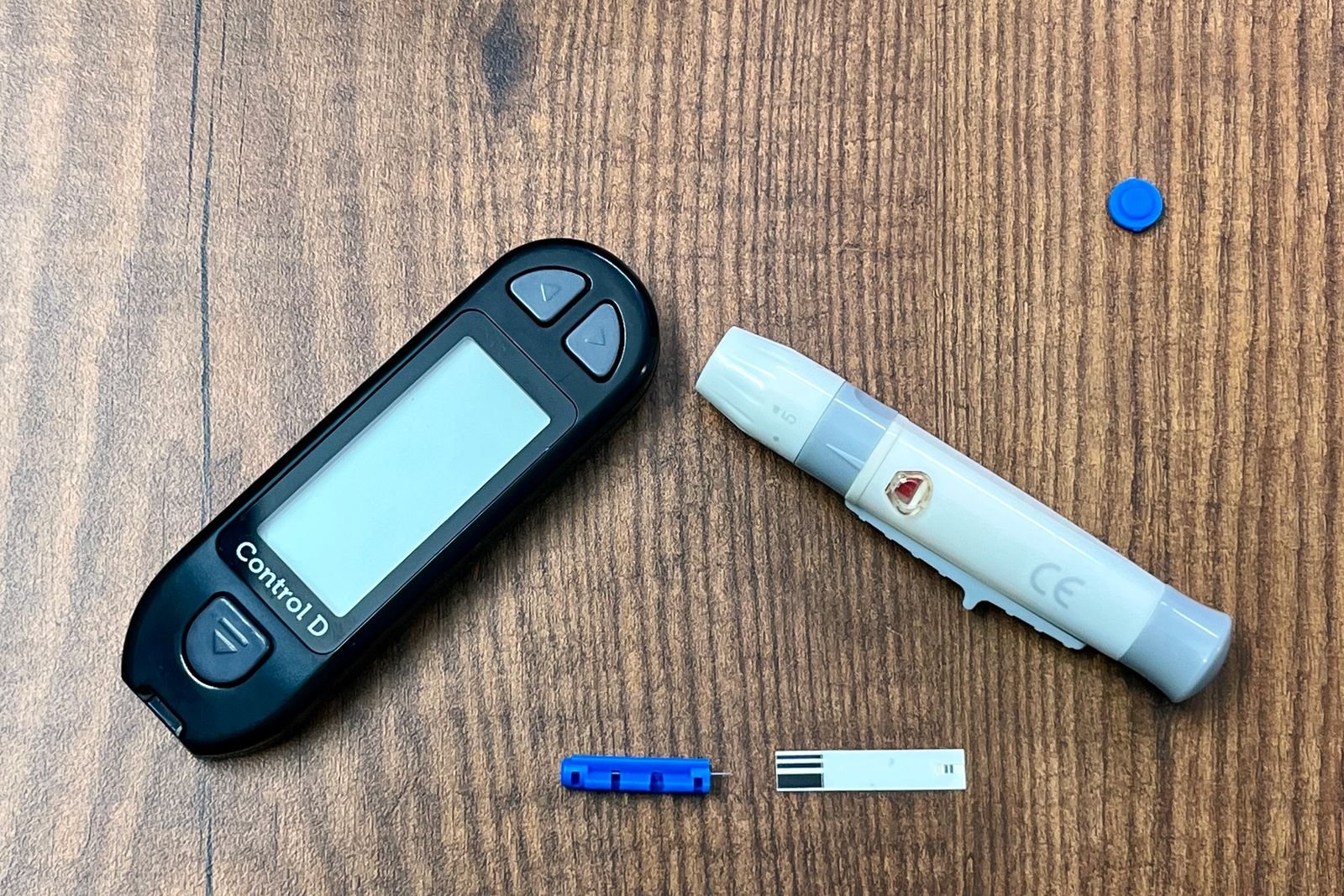 Glucose meter and lancing device on a wooden table, relevant to people choosing sugar free Metamucil