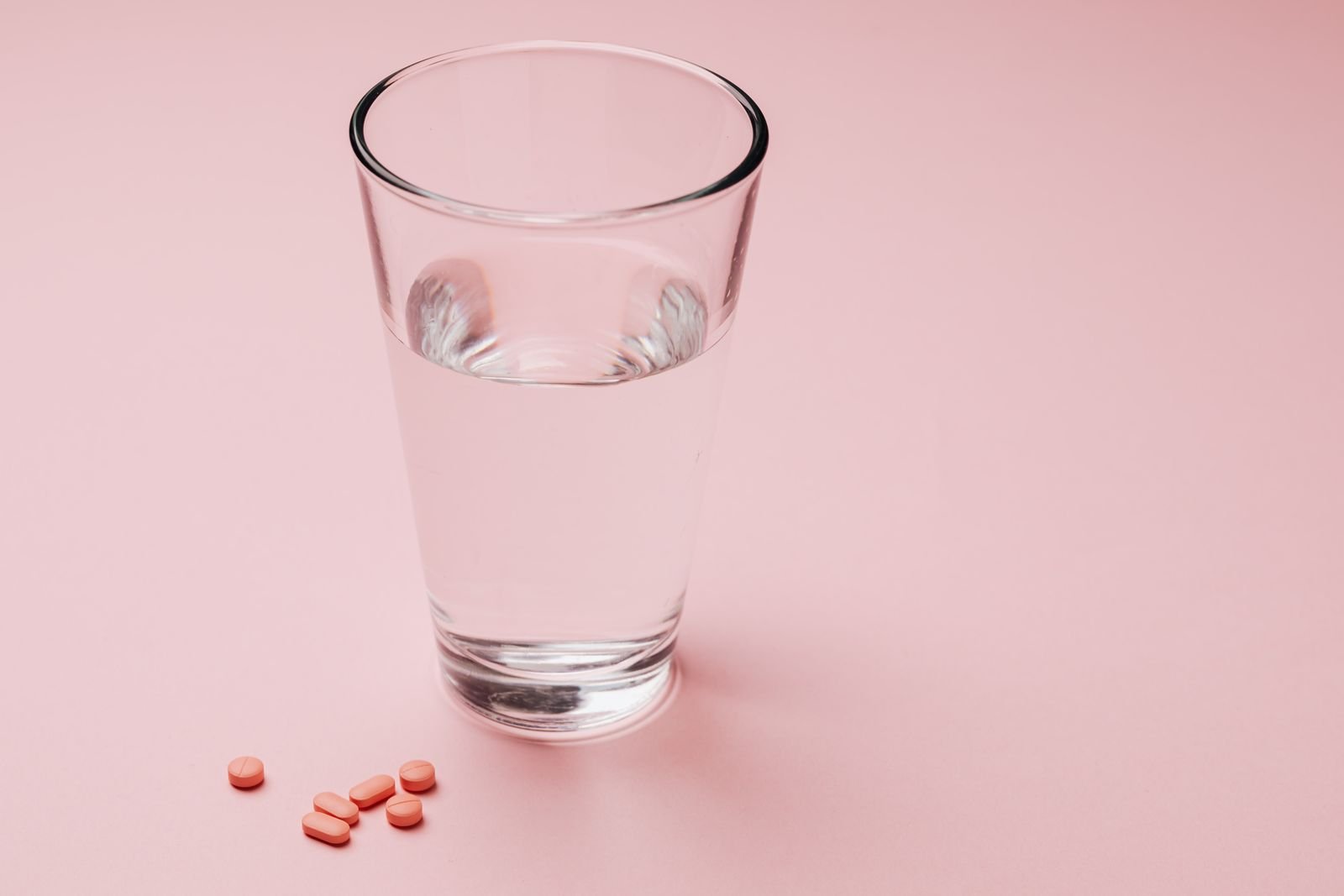 Glass of water next to a few tablets, since drinking fluids helps docusate and senna work