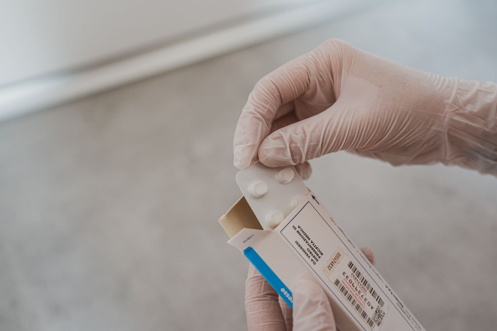 Gloved hands opening a medicine box to read the label, the best way to see how does a hemorrhoid cream work