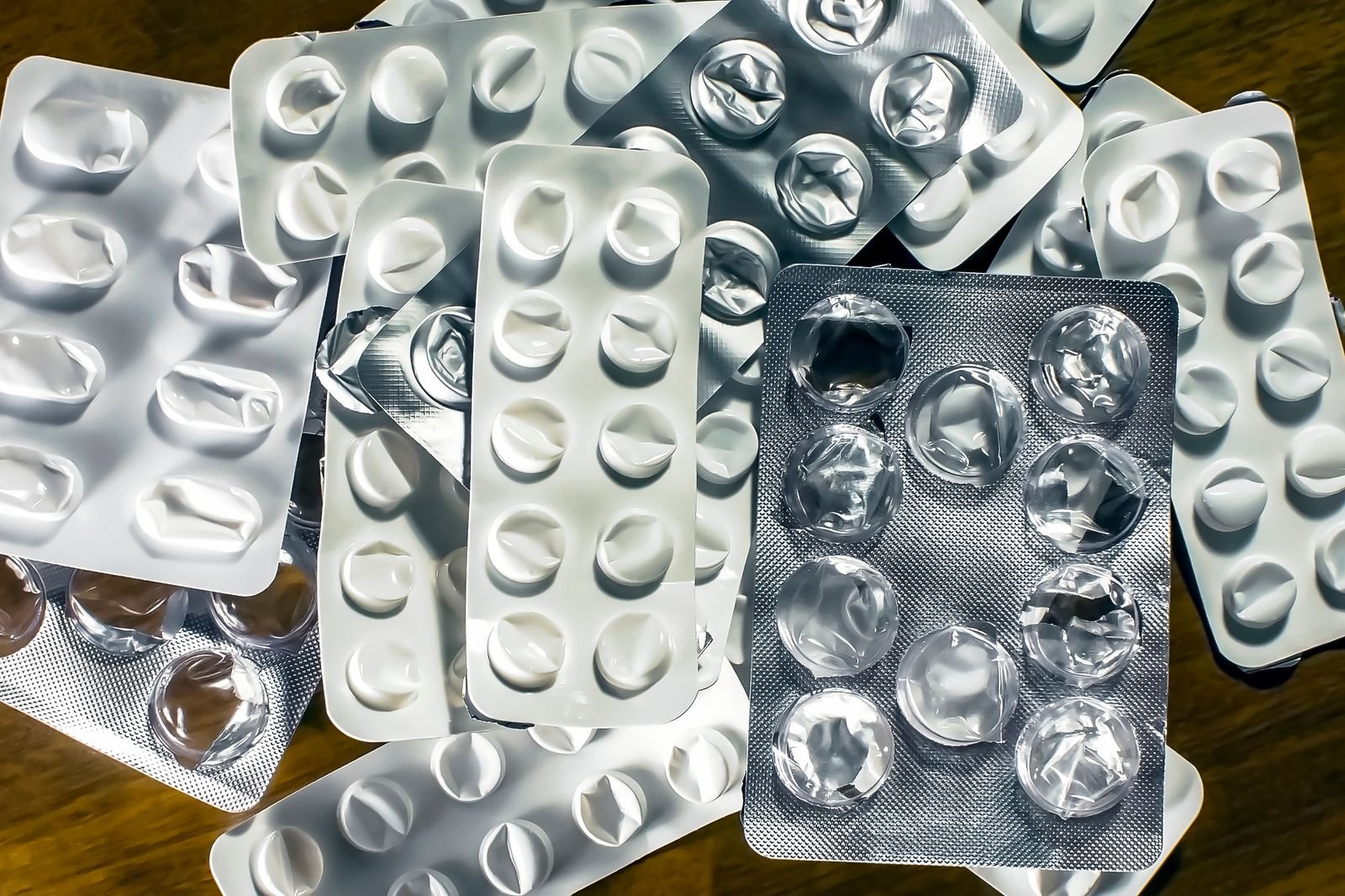 Medication blister packs on a wooden table illustrating how to compare the best hemorrhoid suppositories