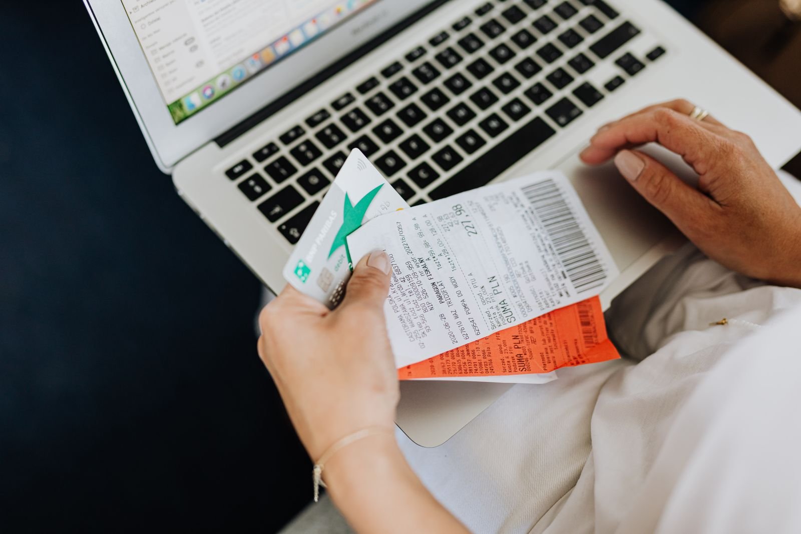 Person holding an itemized receipt beside a laptop, keeping records to show hemorrhoid cream or medication covered by FSA/HSA