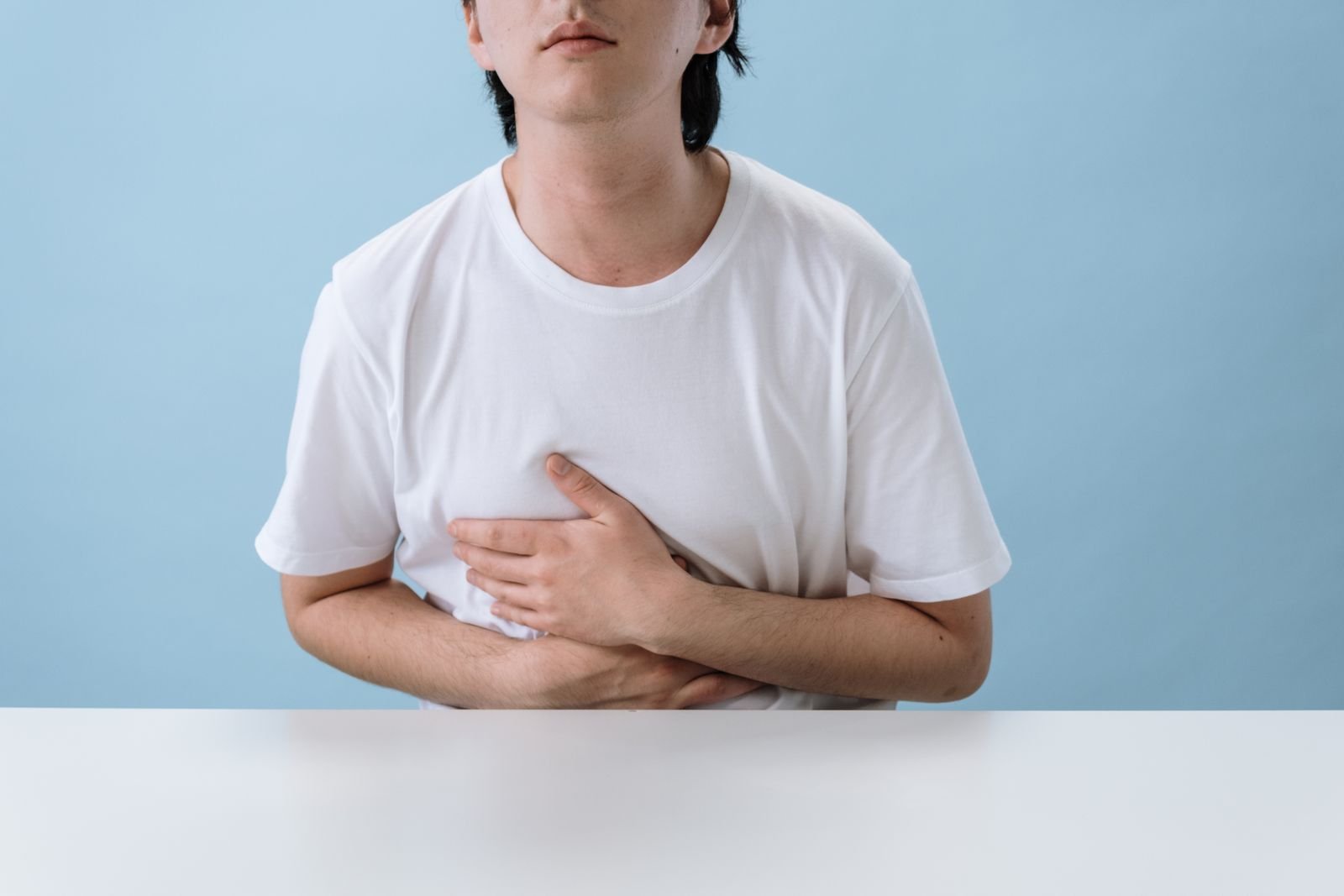 Person holding their stomach in discomfort, a reminder of the stomach and bleeding risks of ibuprofen for hemorrhoids