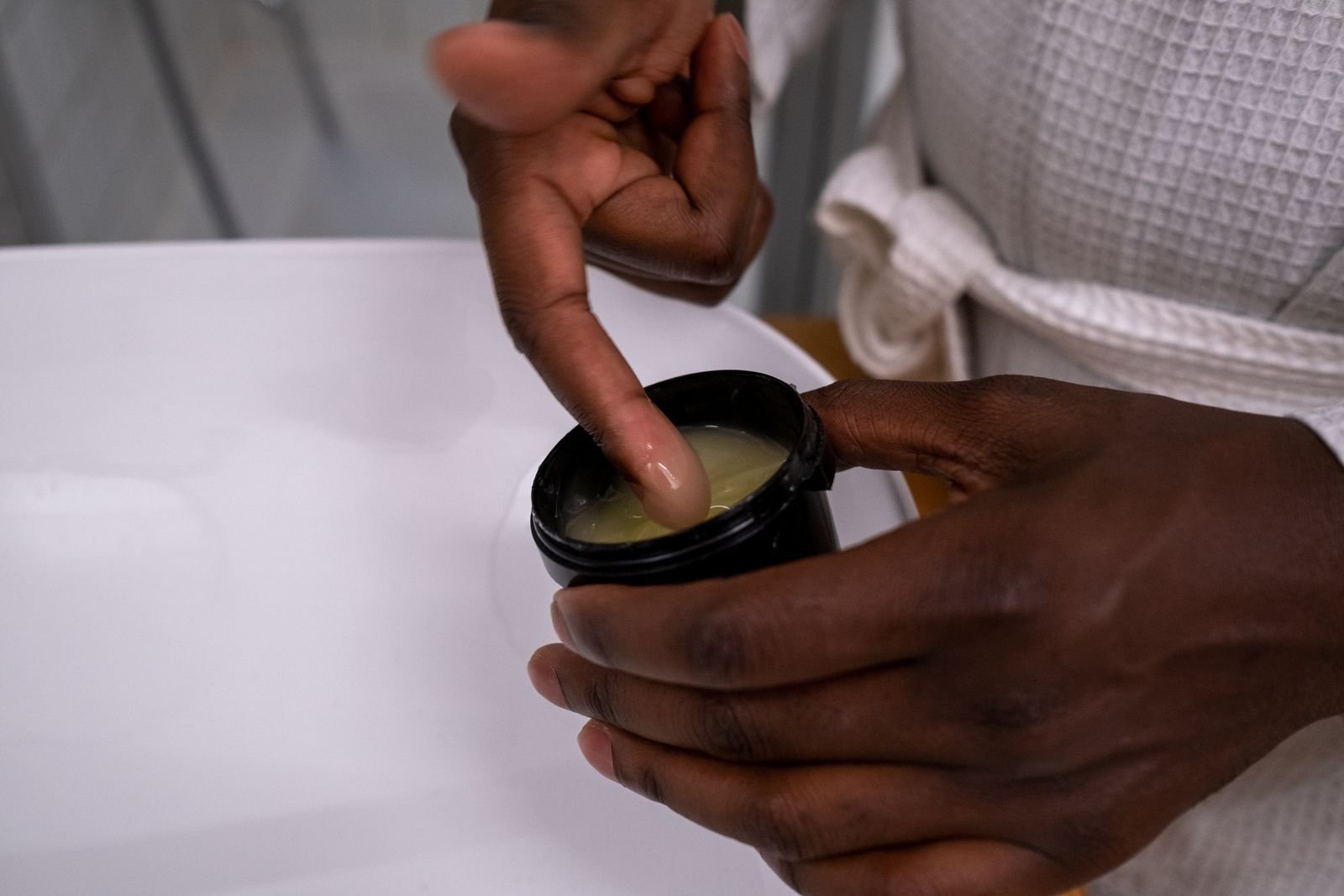 Fingertip dipping into a jar of ointment, the kind of product people ask about in does Preparation H get rid of hemorrhoids