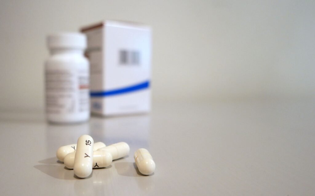 Plain medicine bottle and box with white capsules, the kind of over the counter product asked about in is hemorrhoid cream or medication covered by FSA/HSA