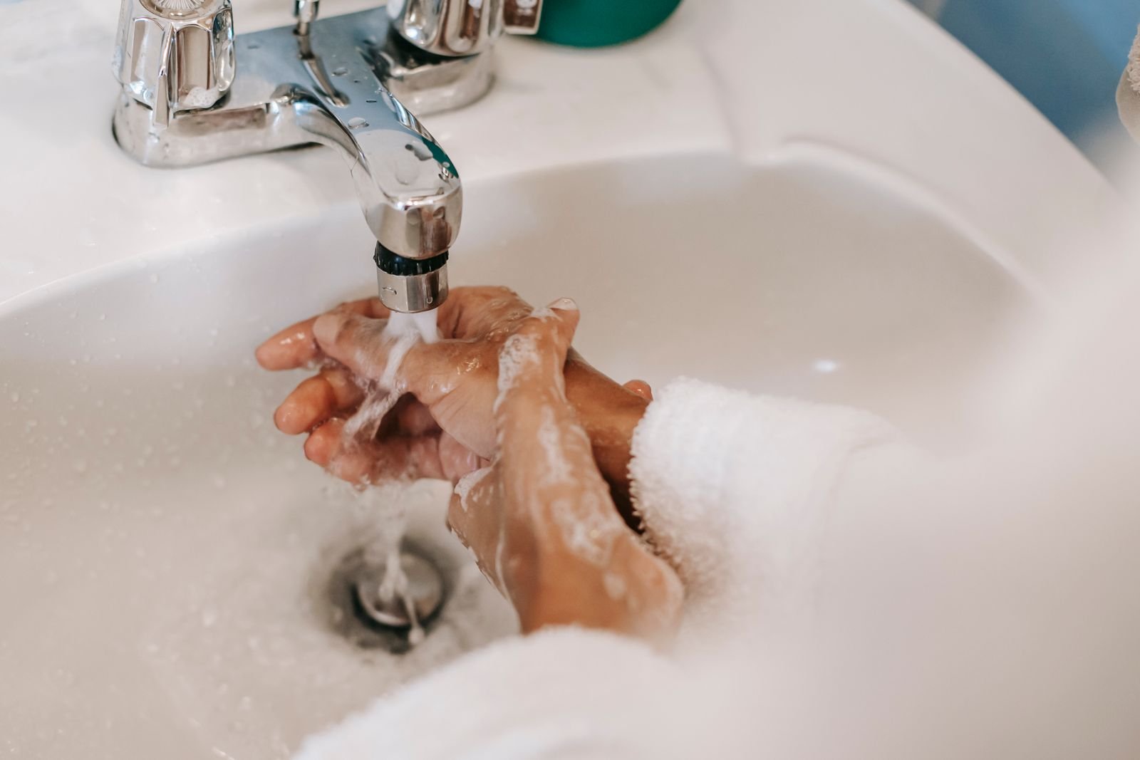 Hands rinsing under a faucet after using hemorrhoidal medicated wipes