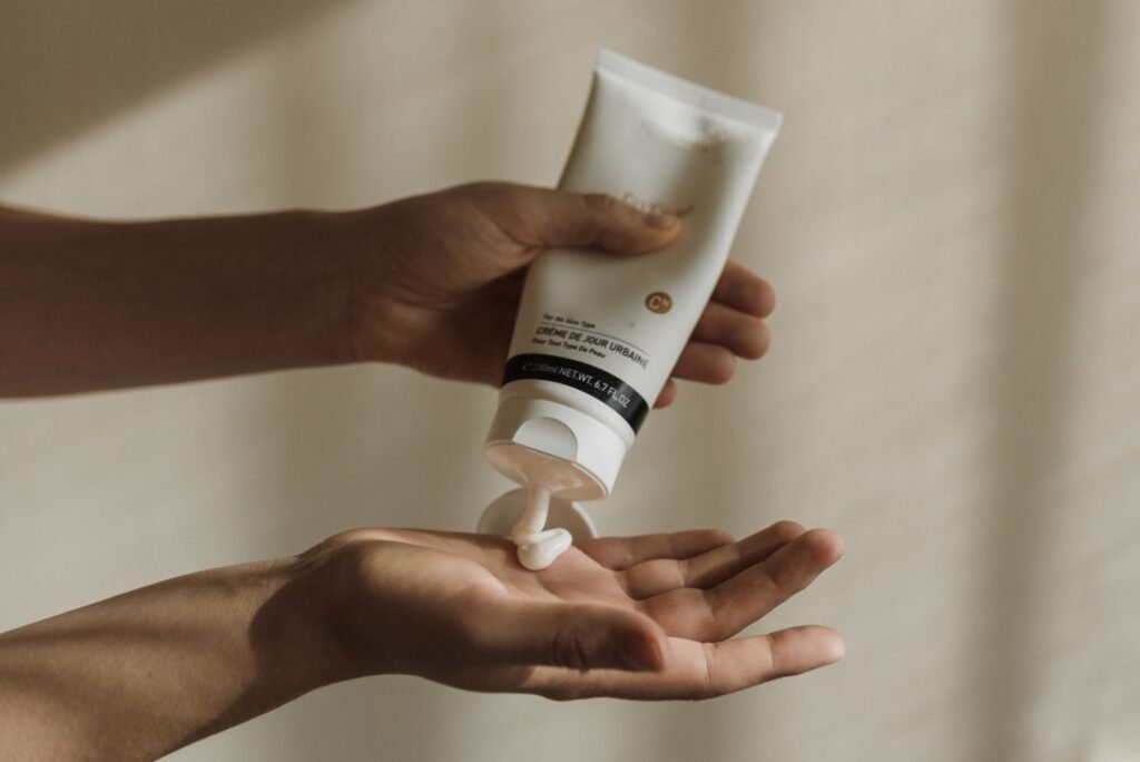 Hand squeezing a white cream tube into the palm, showing how does a hemorrhoid cream work starting with a small amount