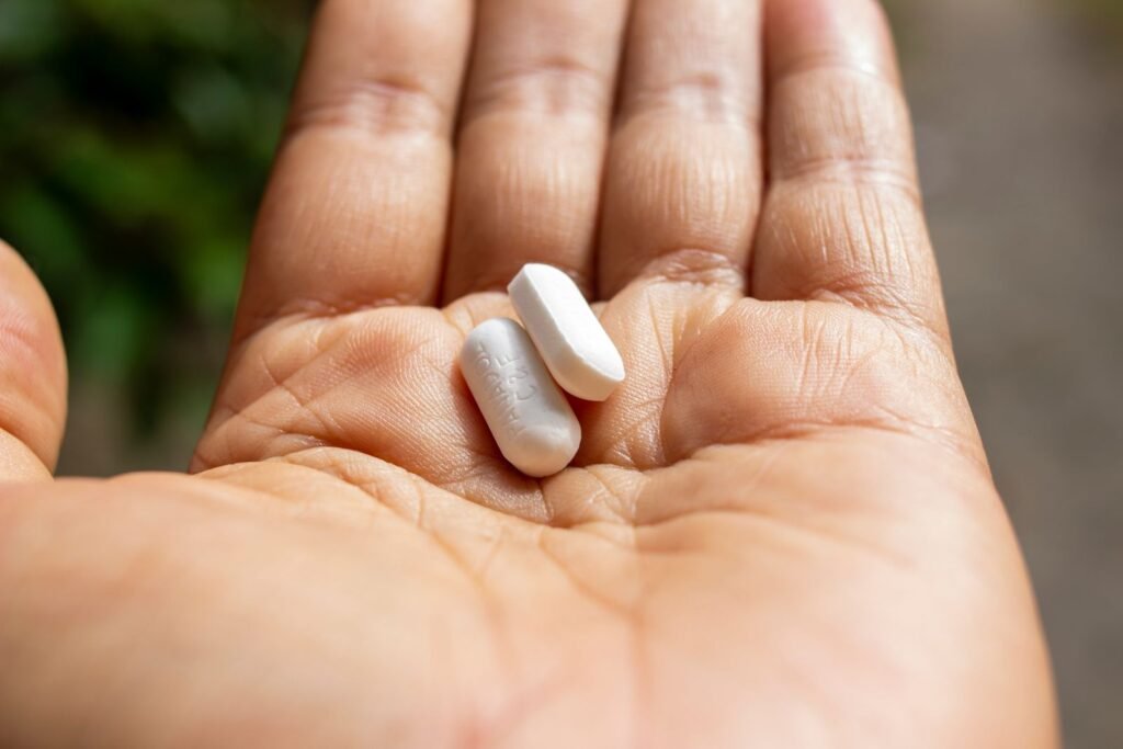Open palm holding two white tablets, illustrating acetaminophen for hemorrhoids and the importance of following label dosing