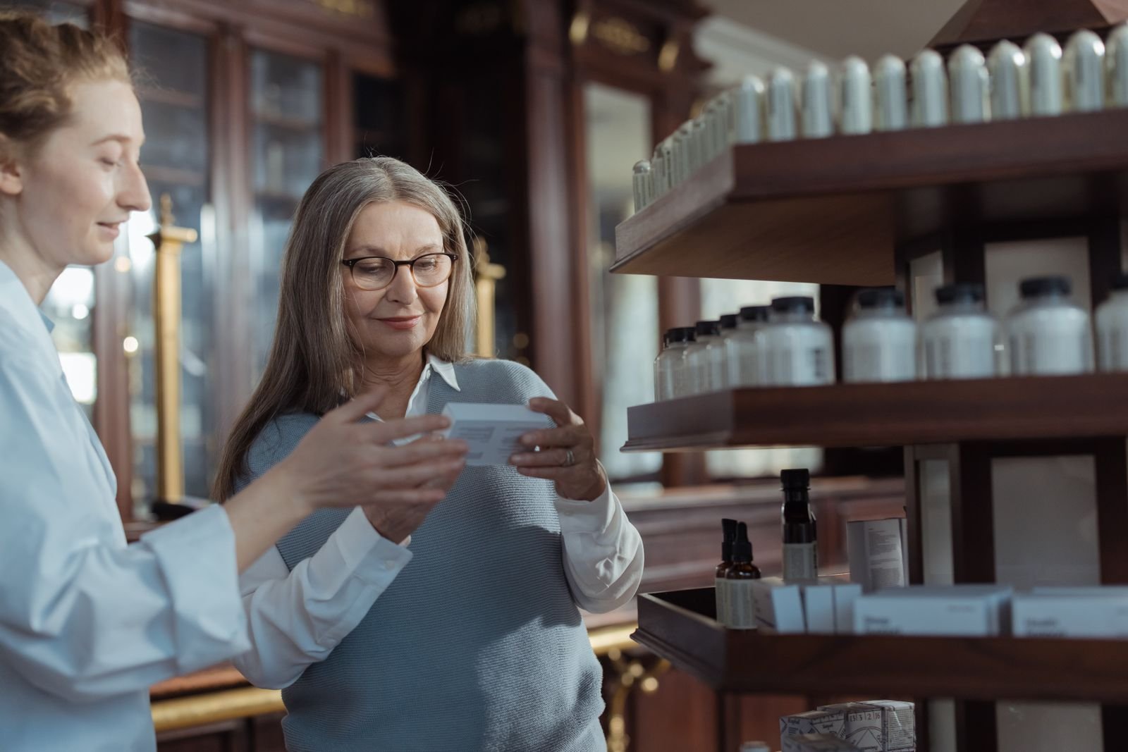 Pharmacist helping an older woman review a product to avoid the risks of using steroid hemorrhoid cream for too long