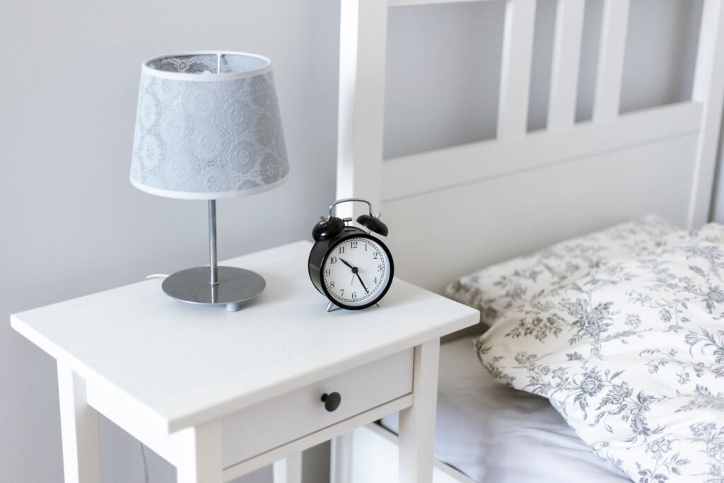 Bedside table with a lamp and alarm clock, since bedtime is a popular time to use Preparation H suppositories
