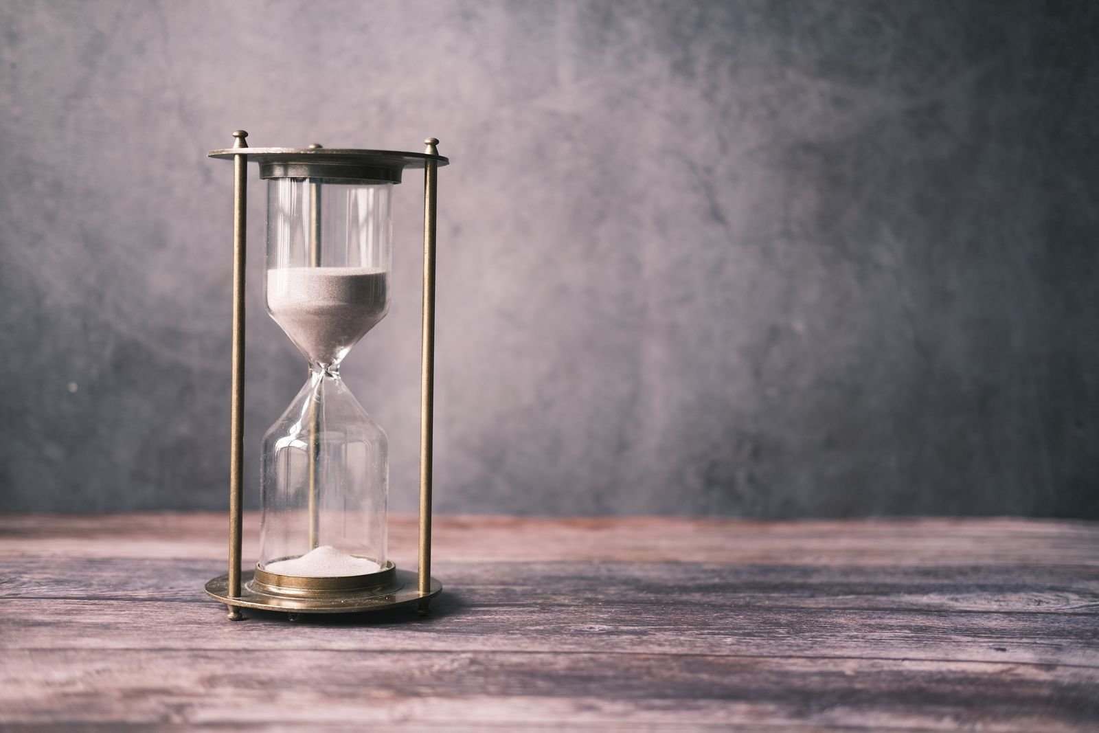 Classic hourglass with sand on a wooden table, representing how long Preparation H takes to work