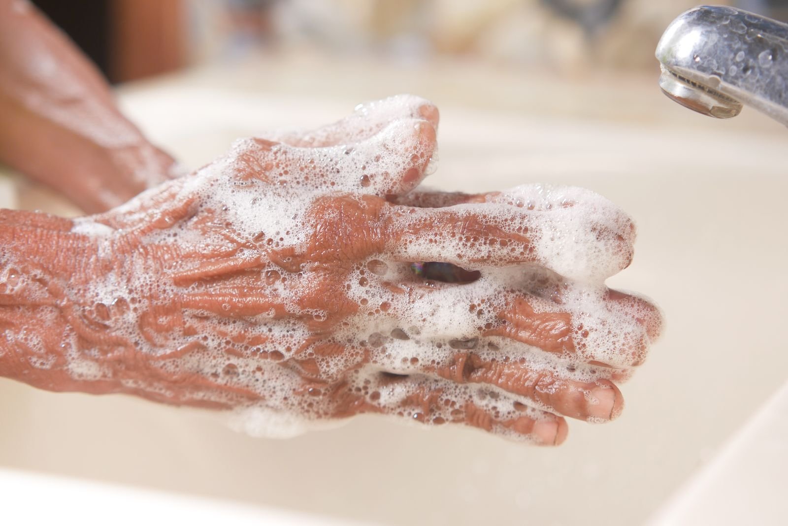 Soapy hands under a running faucet, a simple hygiene step that pairs with Preparation H medicated wipes