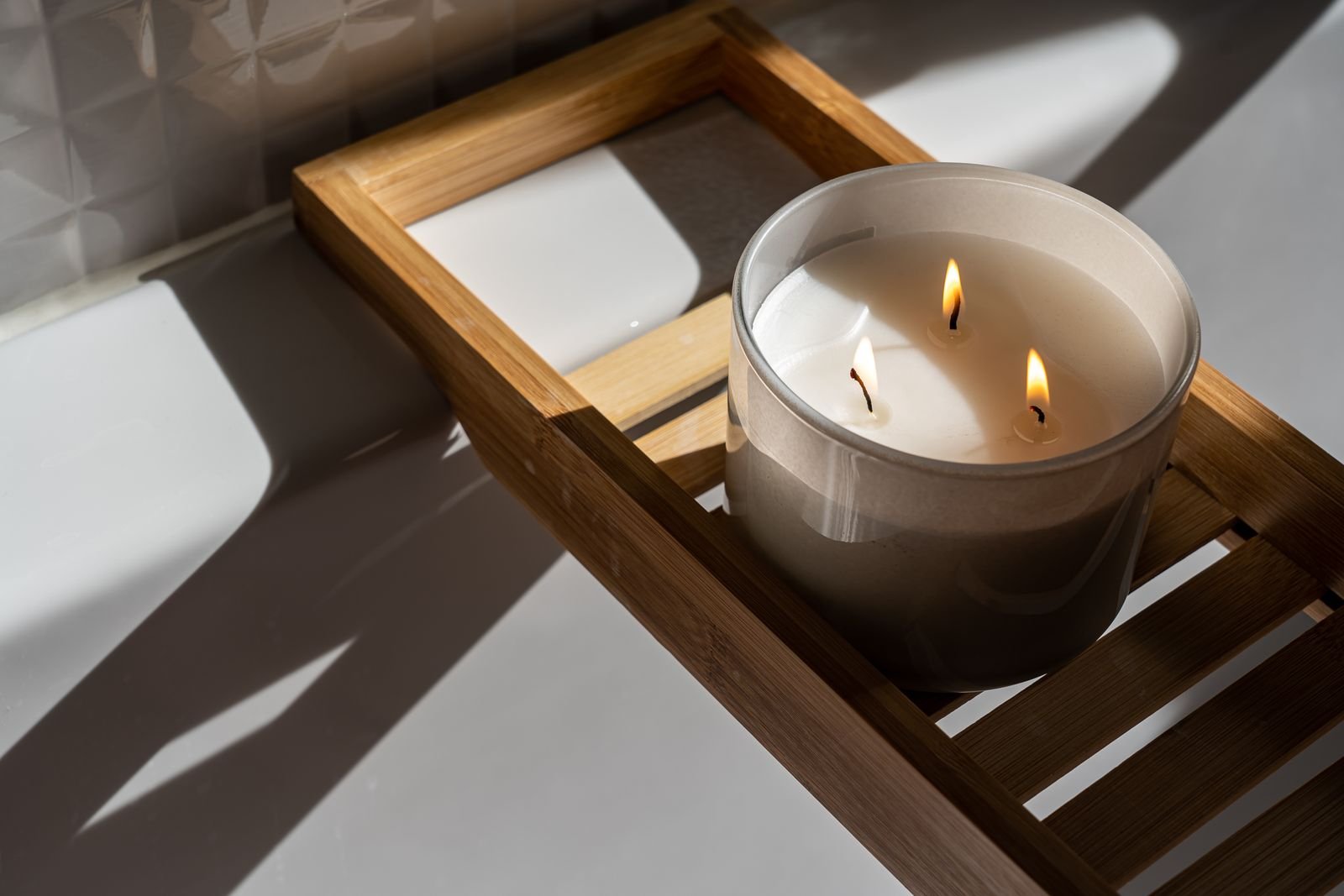 Lit candle on a bathtub tray, a reminder that an aerosol hemorrhoid spray is flammable until dry