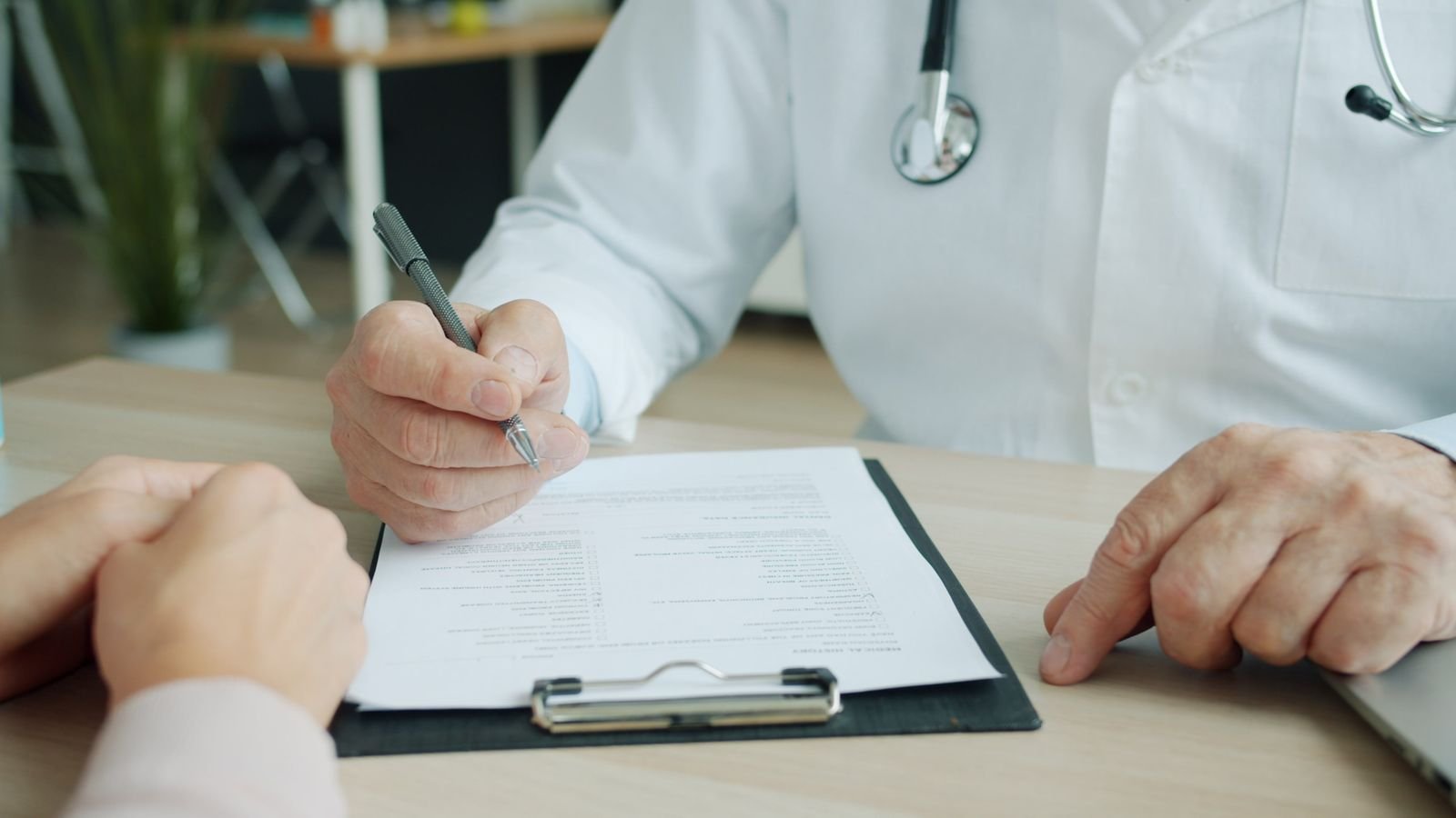 Doctor and patient reviewing notes at a desk while discussing hemorrhoids vs colorectal cancer warning signs